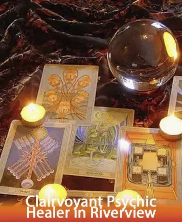 A mystical scene with a crystal ball, Tarot cards, and lit candles on a dark, textured cloth. Warm, ambient lighting creates an enigmatic and inviting atmosphere. Text reads “Clairvoyant Psychic Healer in Riverview.”