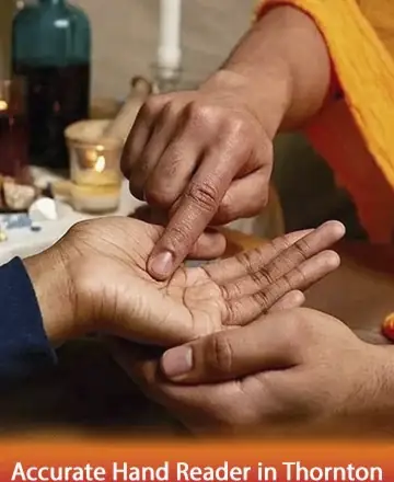 Two individuals are engaged in a palm reading session. One person gently points at the other's palm. The setting is cozy, with warm lighting and candles in the background.